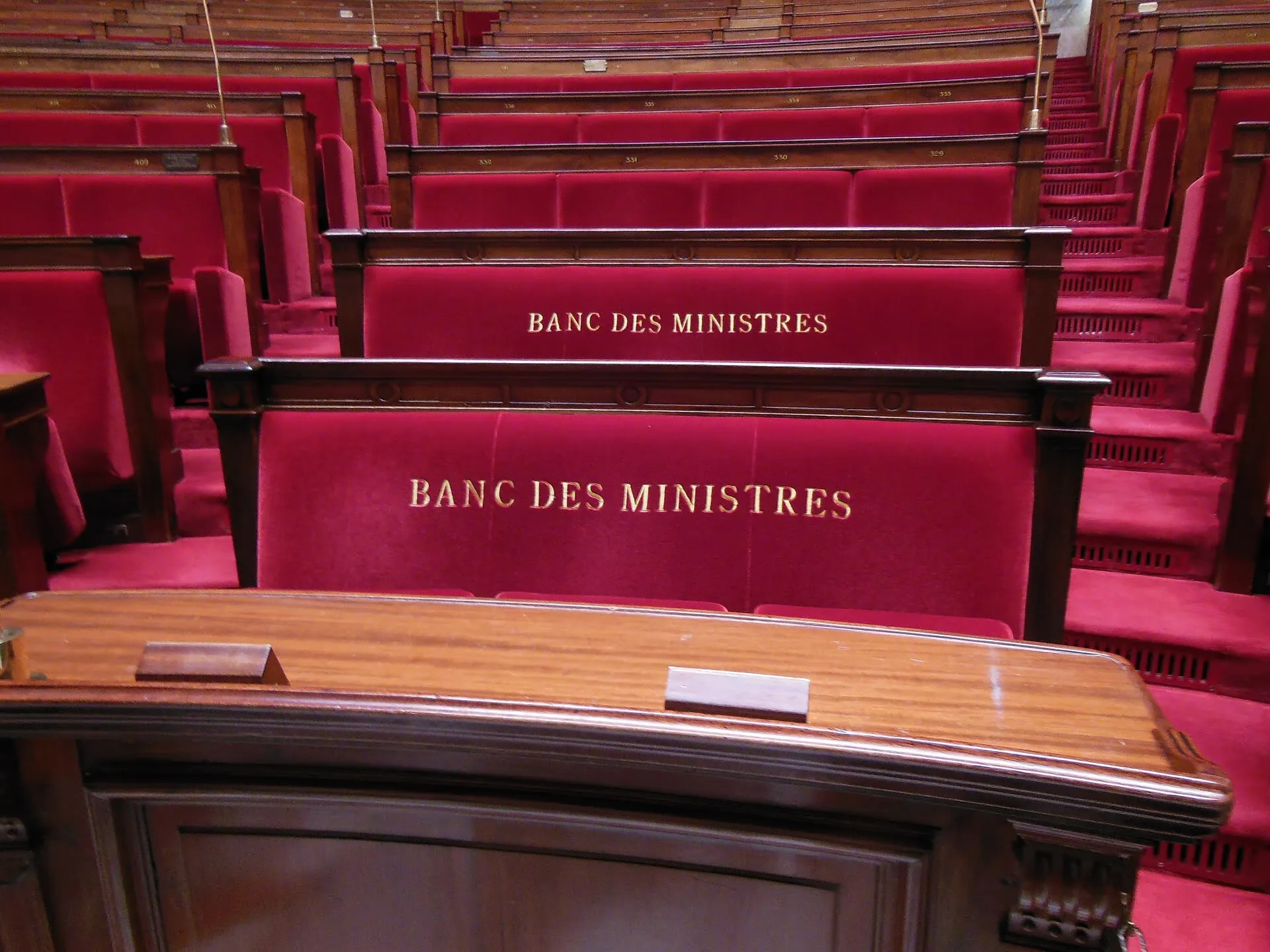 L'hémicycle de l'Assemblée nationale, avec ses rangées de sièges rouges disposées en demi-cercle face à la tribune.