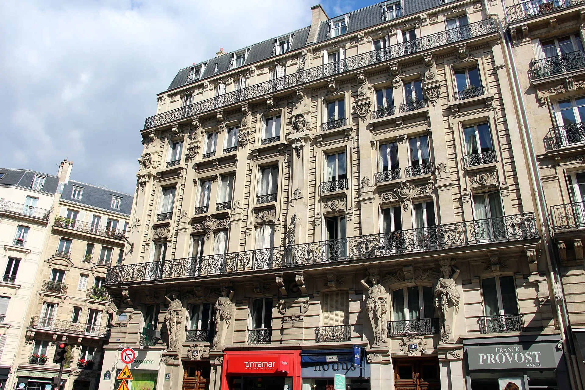 Façade d'un immeuble haussmannien en pierre de taille, aux 105 et 107 rue de Rennes à Paris, avec ses balcons en fer forgé.