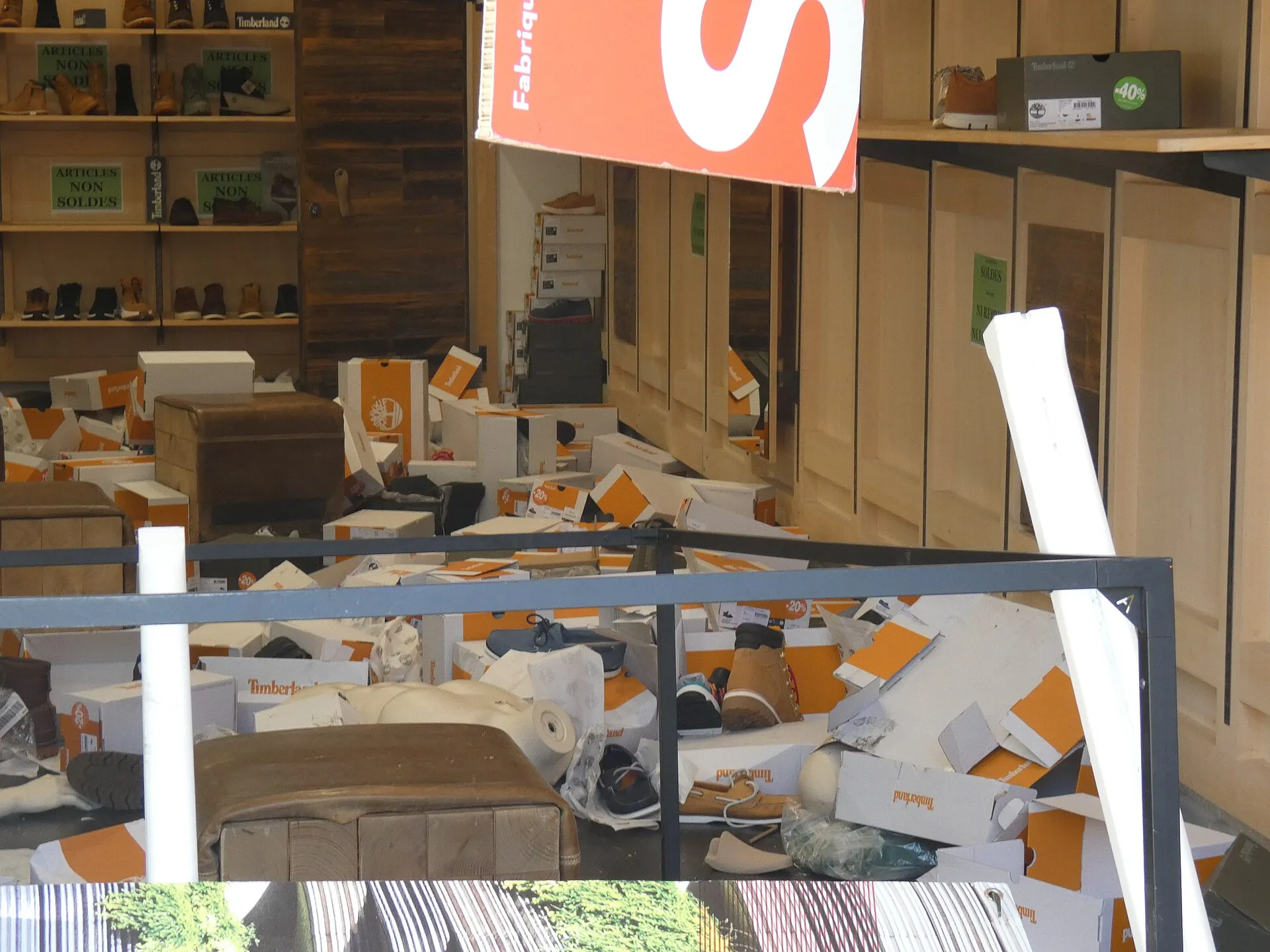 La devanture d'un commerce pillé à Grenoble au lendemain des émeutes de 2023, vitrine brisée et protégée par des panneaux.