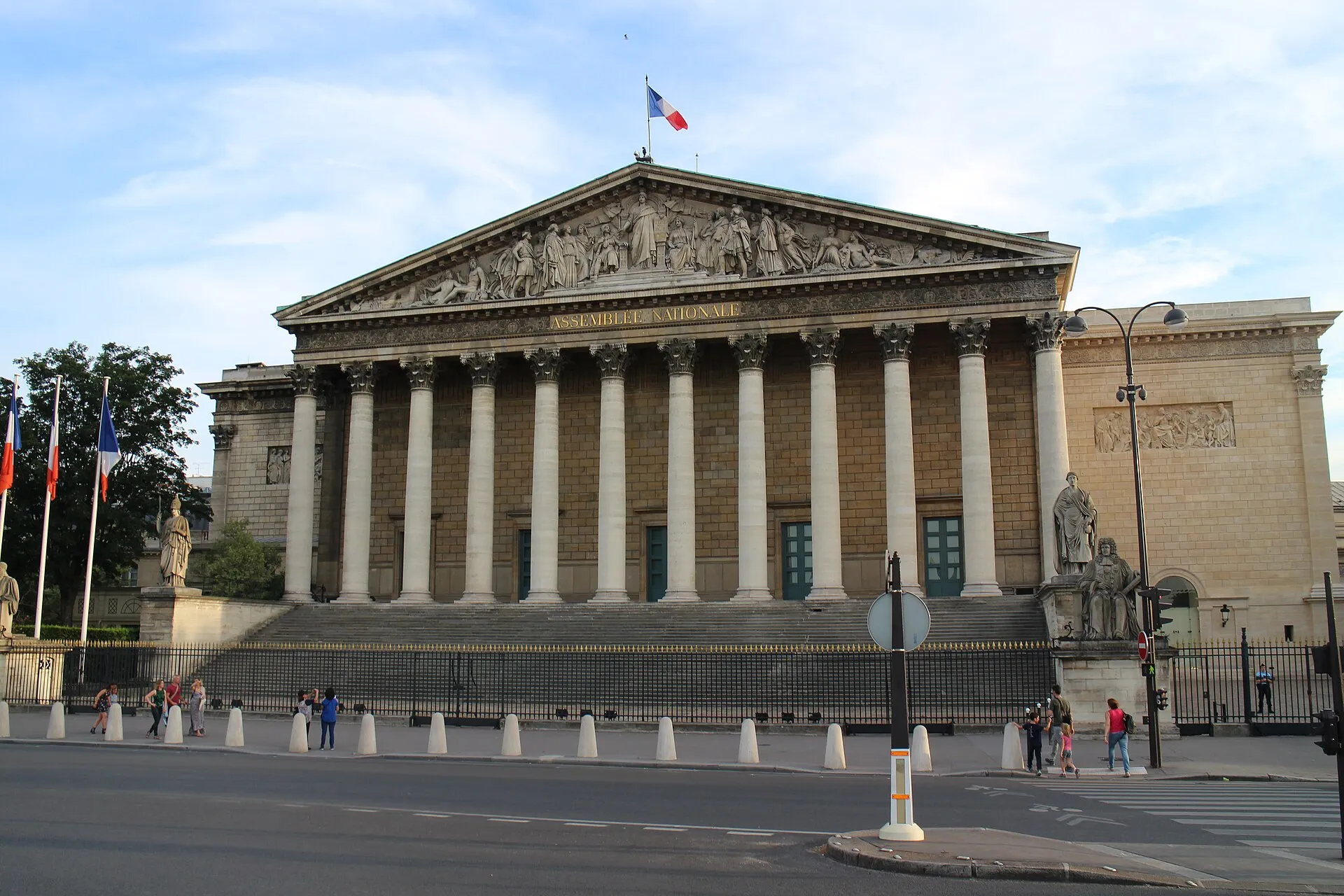 La façade à colonnes du Palais Bourbon, siège de l'Assemblée nationale à Paris, sous un ciel bleu.