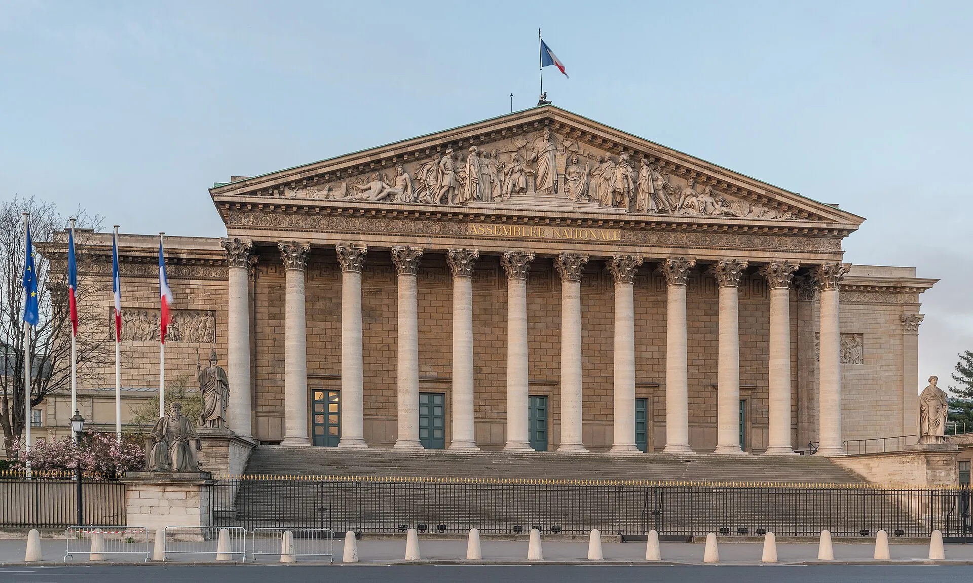 Façade à colonnes du Palais Bourbon, siège de l'Assemblée nationale à Paris, vue depuis le nord-ouest sous un ciel bleu.