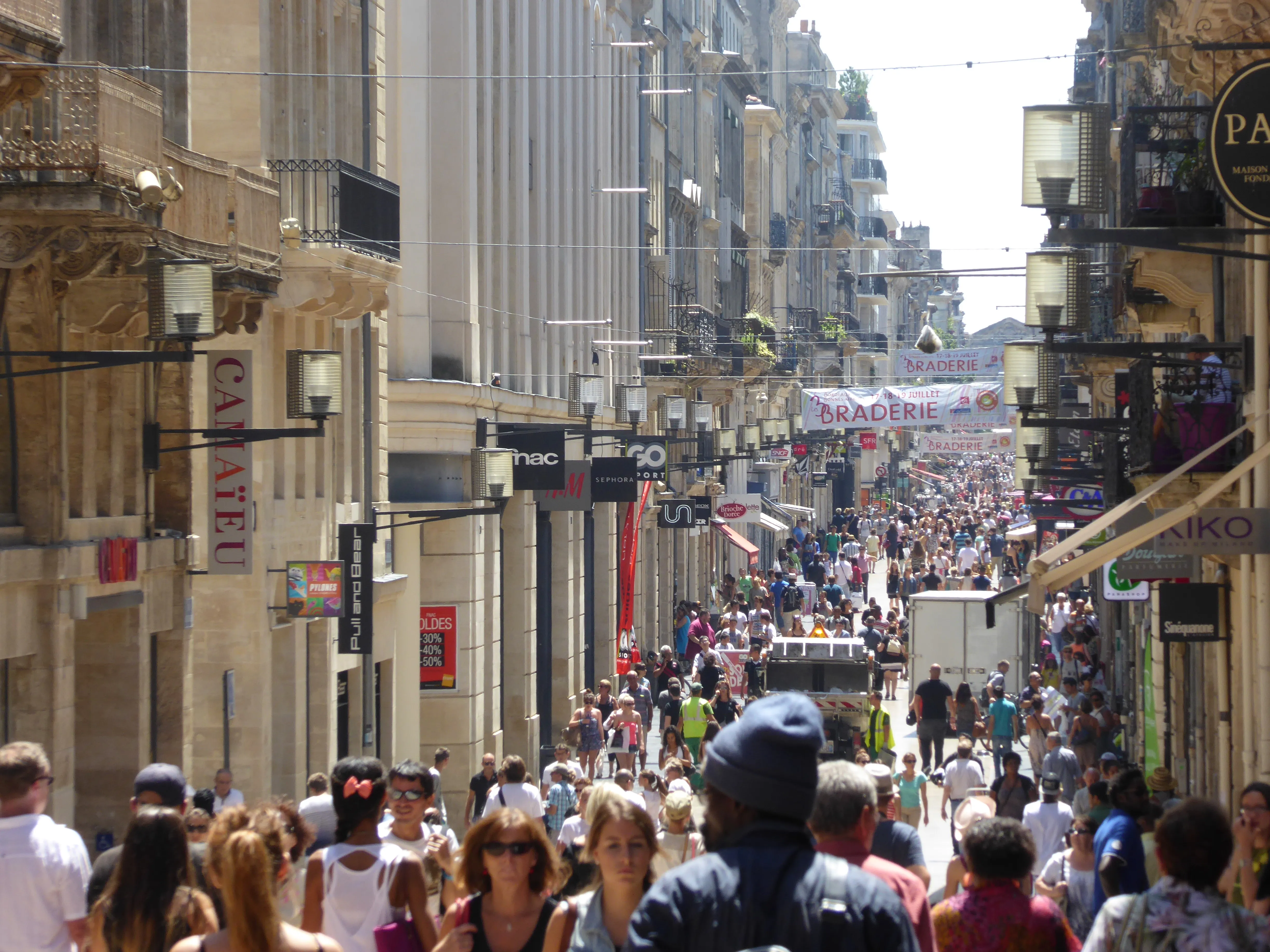 La rue Sainte-Catherine à Bordeaux, rue piétonne commerçante bordée d'immeubles en pierre claire, en plein été.