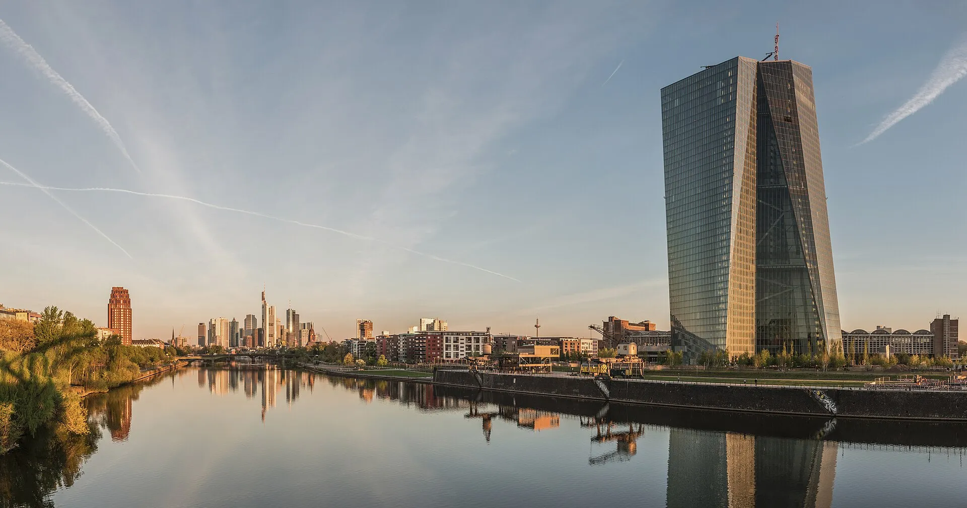 Le siège de la Banque centrale européenne à Francfort, une tour de verre à deux pans, devant la skyline de la ville à l'aube.