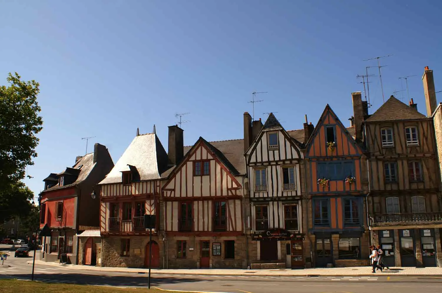 Une rangée de maisons anciennes à pans de bois colorés sur le port de Vannes, en Bretagne, sous un ciel bleu.