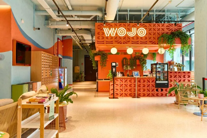 Intérieur d'un espace de coworking Wojo, enseigne lumineuse et mobilier convivial
